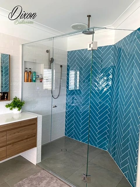 Walk-in shower with a teal herringbone feature wall, white subway tile and a tiled niche